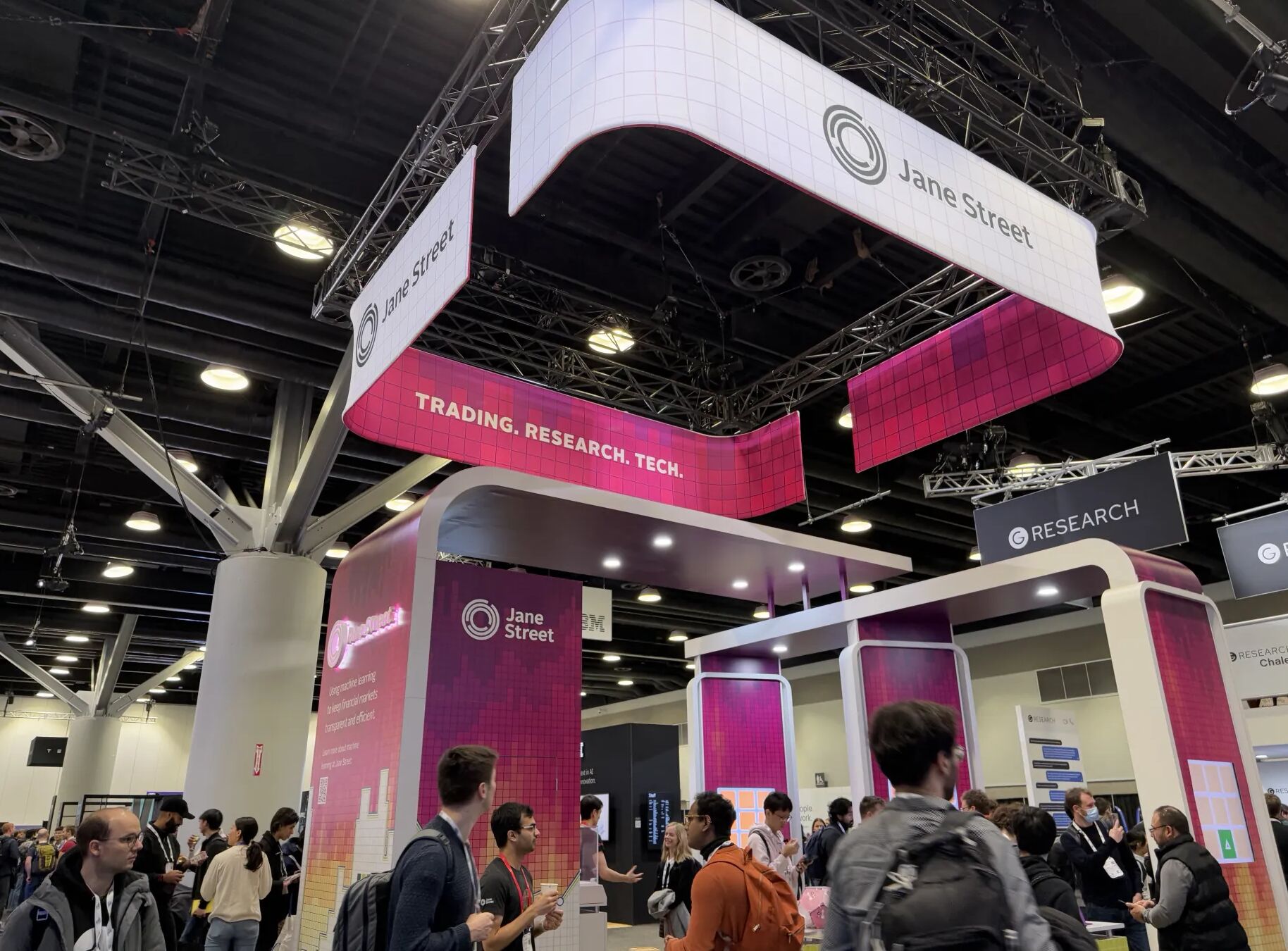 Attendees gathering beneath a large Jane Street exhibition sign at ICLR 2025.